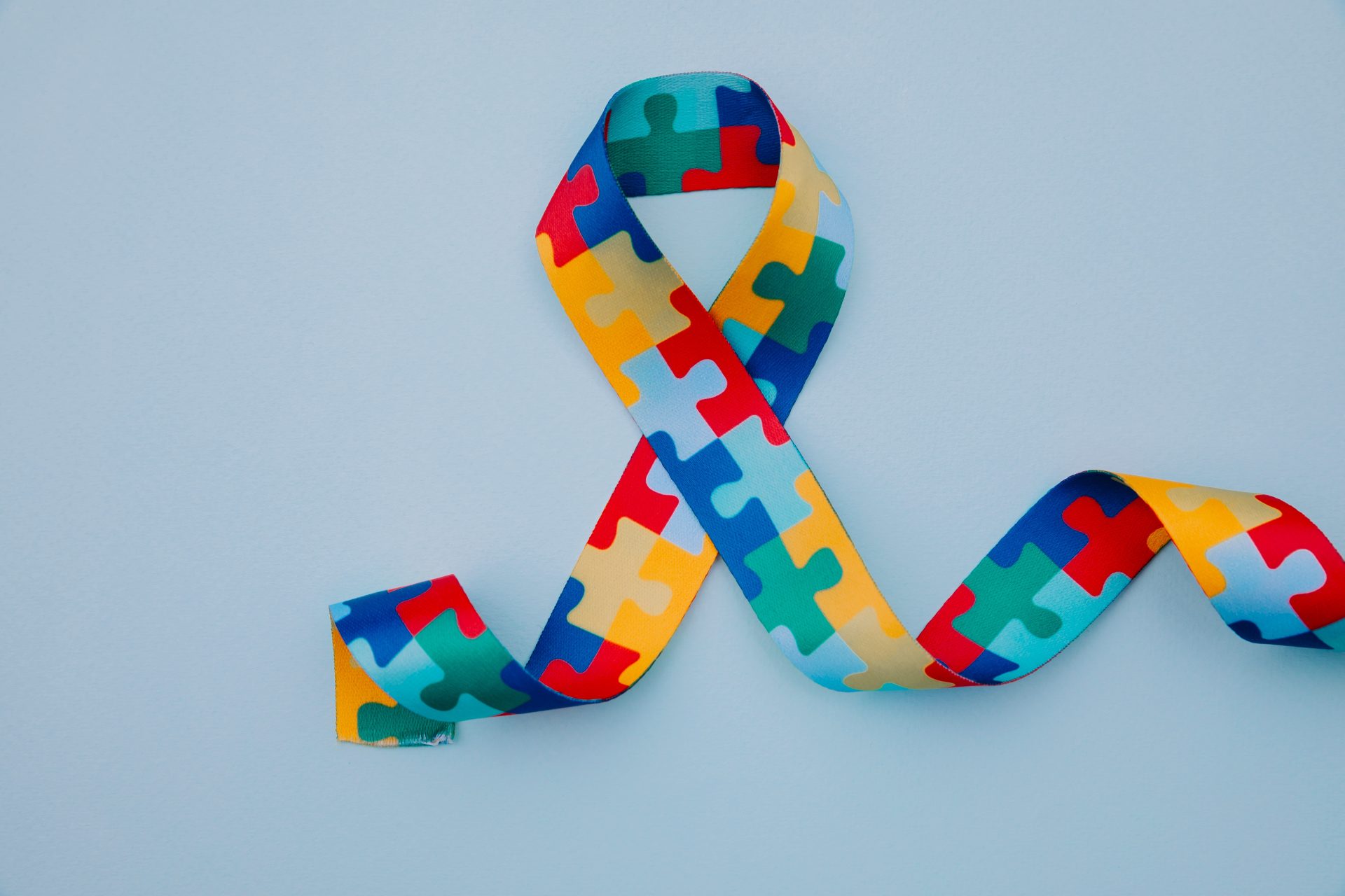 world-autism-awareness-pride-day-with-puzzle-pattern-ribbon-blue-background